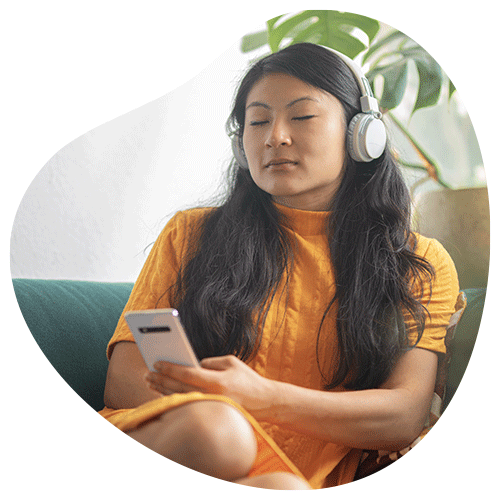 Vrouw die met een headset op luistert naar een mindfulness oefening op haar telefoon