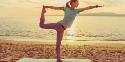 Op de afbeelding een vrouw op het strand die yoga doet.