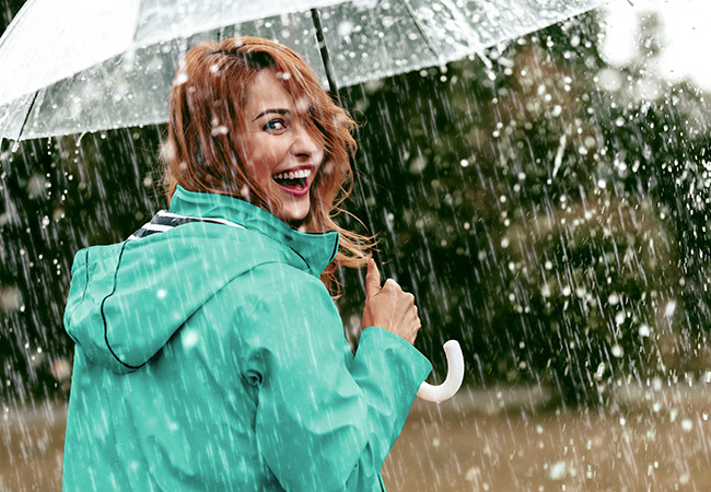 Lachende vrouw met paraplu in de regen