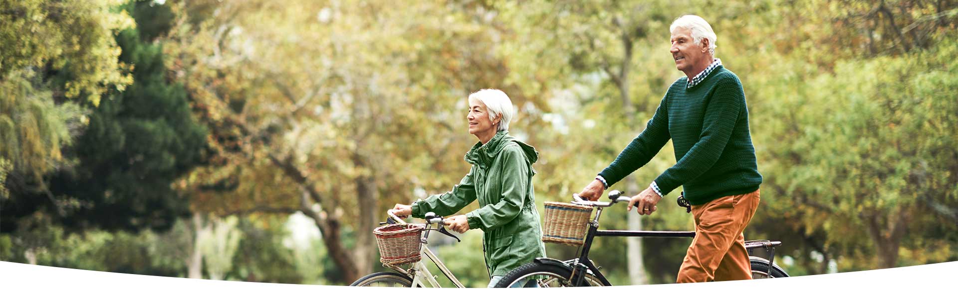 Oudere man en vrouw wandelen met fiets aan de hand